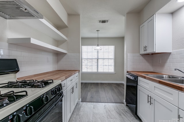 kitchen with white range with gas cooktop, butcher block countertops, range hood, dishwasher, and backsplash