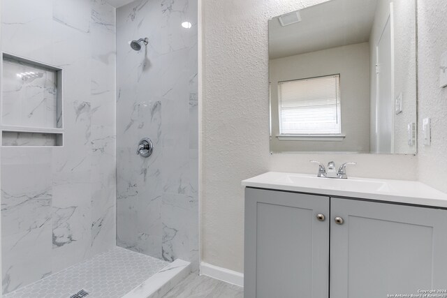 bathroom with tiled shower and vanity