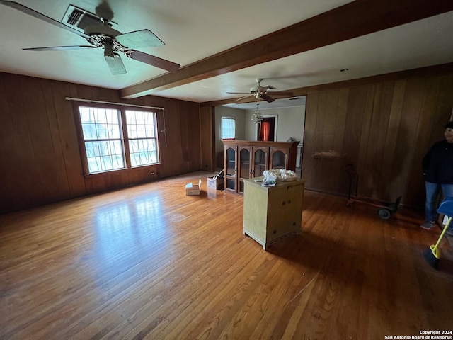 interior space featuring beamed ceiling, wood-type flooring, ceiling fan, and wooden walls