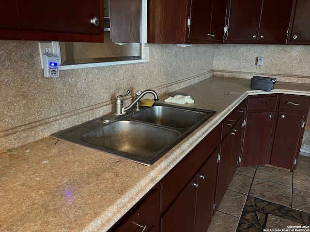 kitchen featuring dark brown cabinetry, sink, backsplash, and tile floors