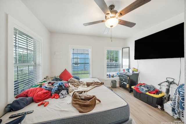 bedroom with ceiling fan, light hardwood / wood-style floors, and multiple windows