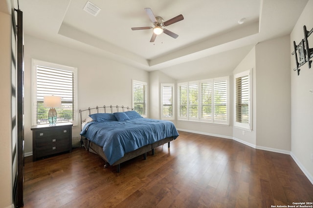 bedroom featuring ceiling fan, a tray ceiling, and dark hardwood / wood-style floors