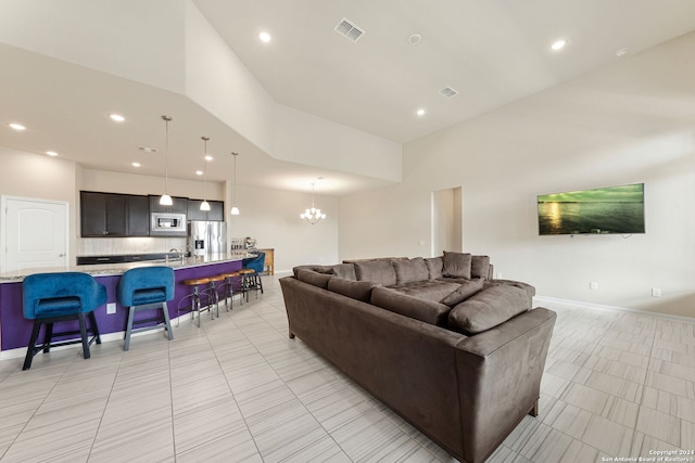 tiled living room with sink, a notable chandelier, and a high ceiling