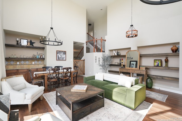 living room featuring wood-type flooring, a chandelier, and a high ceiling