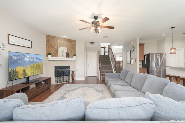 living room with a large fireplace, ceiling fan, and dark hardwood / wood-style floors