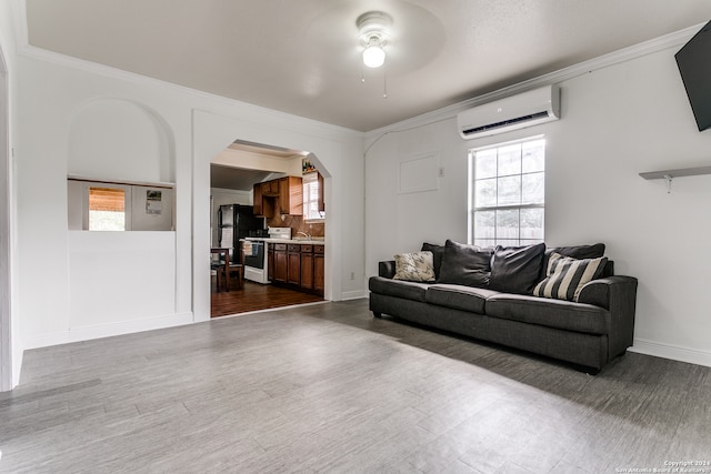 living room featuring a wall unit AC, ceiling fan, hardwood / wood-style flooring, and a wealth of natural light