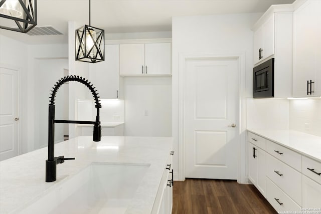 kitchen with white cabinets, dark hardwood / wood-style flooring, backsplash, and pendant lighting