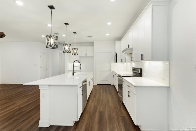 kitchen featuring white cabinets, decorative light fixtures, stainless steel appliances, dark hardwood / wood-style floors, and an island with sink