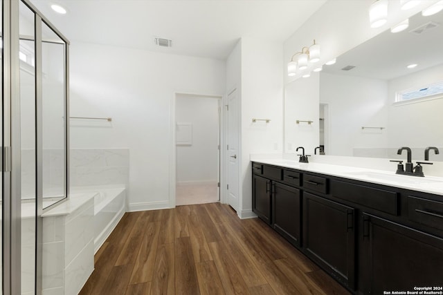 bathroom featuring wood-type flooring, double vanity, and tiled bath