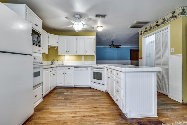 kitchen with kitchen peninsula, white cabinets, white appliances, and light hardwood / wood-style floors