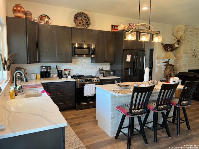 kitchen with gas stove, sink, tasteful backsplash, black fridge with ice dispenser, and hardwood / wood-style flooring