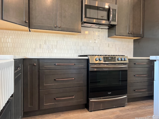 kitchen featuring tasteful backsplash, appliances with stainless steel finishes, light hardwood / wood-style flooring, and dark brown cabinetry