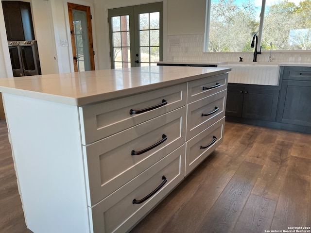 kitchen with wood-type flooring, tasteful backsplash, sink, and washer and clothes dryer