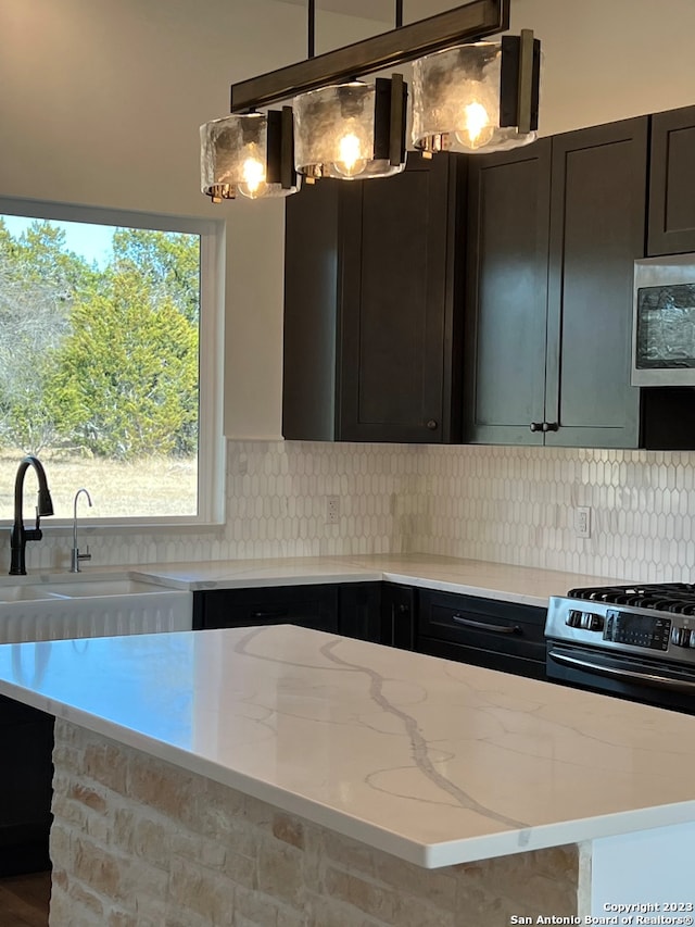 kitchen with backsplash, sink, stainless steel microwave, and stove