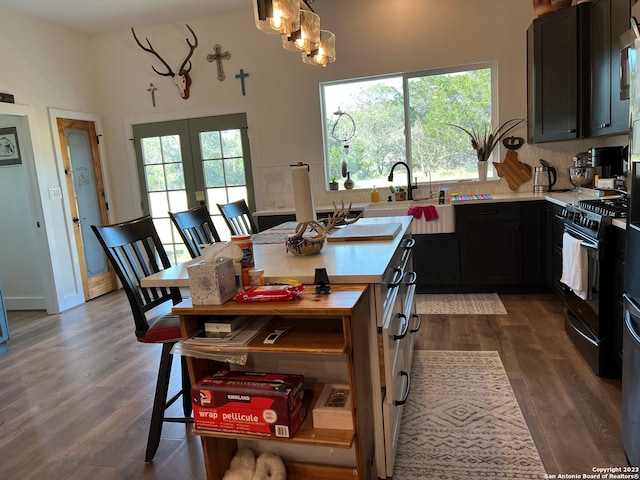 kitchen featuring butcher block countertops, wood-type flooring, sink, pendant lighting, and black gas range oven