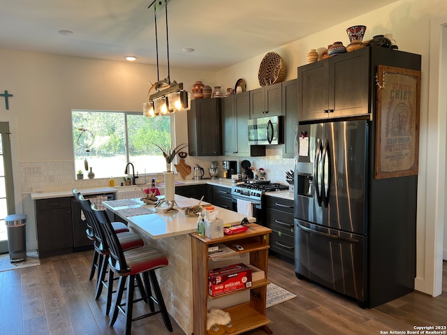 kitchen with a kitchen island, tasteful backsplash, appliances with stainless steel finishes, and dark hardwood / wood-style floors