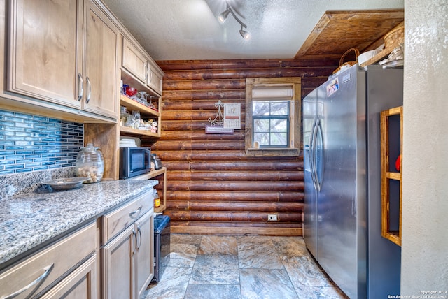 kitchen with rail lighting, backsplash, log walls, stainless steel appliances, and a textured ceiling