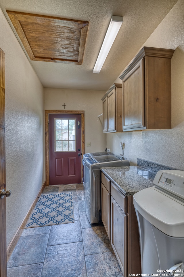 laundry area with cabinets, independent washer and dryer, light tile floors, and a textured ceiling