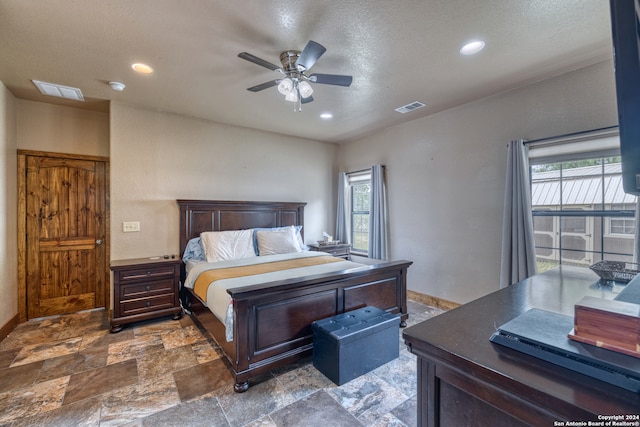 tiled bedroom featuring ceiling fan, multiple windows, and a textured ceiling