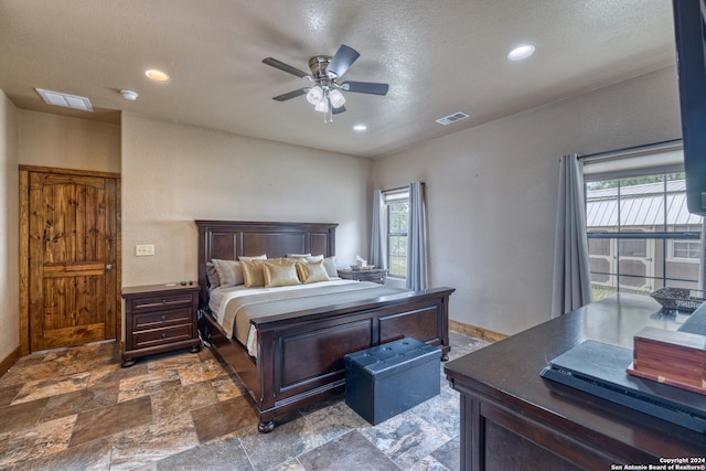 tiled bedroom with ceiling fan, multiple windows, and a textured ceiling