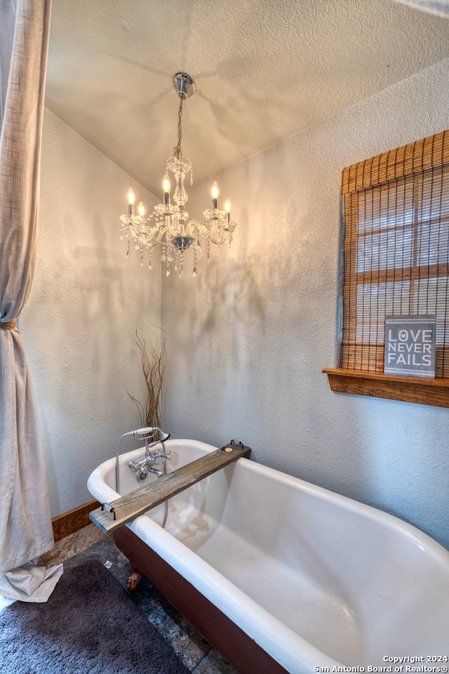 bathroom featuring a chandelier, a bathing tub, and a textured ceiling