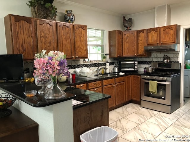 kitchen featuring backsplash, sink, stainless steel range with gas cooktop, and light tile floors