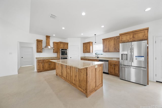 kitchen with a center island, wall chimney exhaust hood, light stone countertops, sink, and appliances with stainless steel finishes