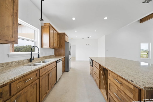 kitchen with light stone countertops, decorative light fixtures, a kitchen island, sink, and appliances with stainless steel finishes