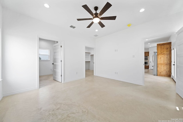 unfurnished bedroom featuring a walk in closet, a closet, stainless steel fridge, and ceiling fan