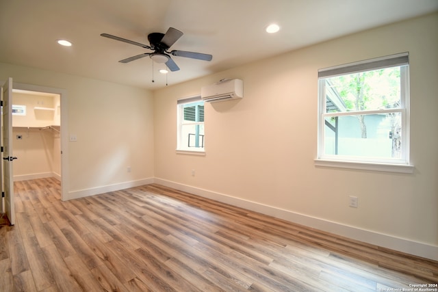 empty room featuring hardwood / wood-style floors, ceiling fan, and a wall mounted AC