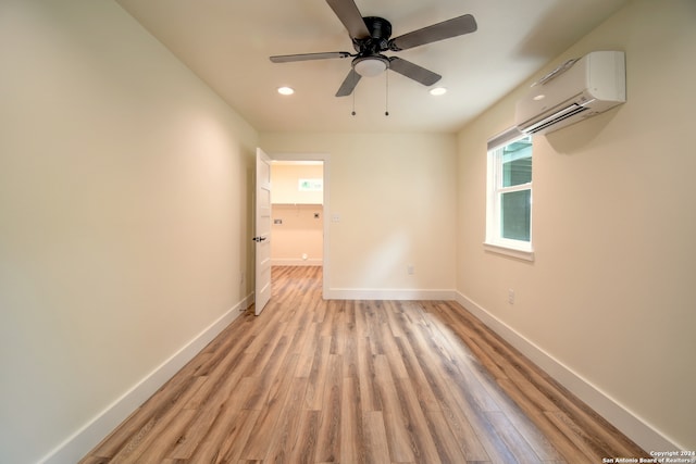 spare room with ceiling fan, light wood-type flooring, and a wall mounted AC