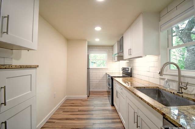 kitchen with light stone countertops, light hardwood / wood-style floors, white cabinetry, sink, and range with electric cooktop