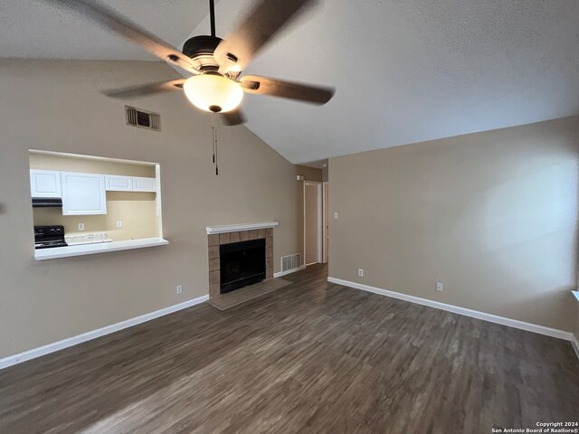 unfurnished living room featuring high vaulted ceiling, dark hardwood / wood-style floors, a tiled fireplace, and ceiling fan