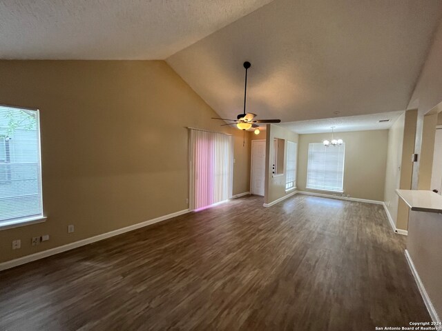 unfurnished living room with high vaulted ceiling, dark hardwood / wood-style flooring, and ceiling fan with notable chandelier