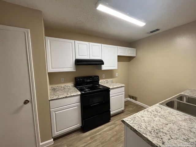 kitchen with white cabinets, hardwood / wood-style floors, sink, light stone counters, and black electric range