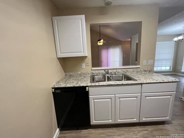 kitchen with black dishwasher, ceiling fan with notable chandelier, hardwood / wood-style floors, sink, and lofted ceiling