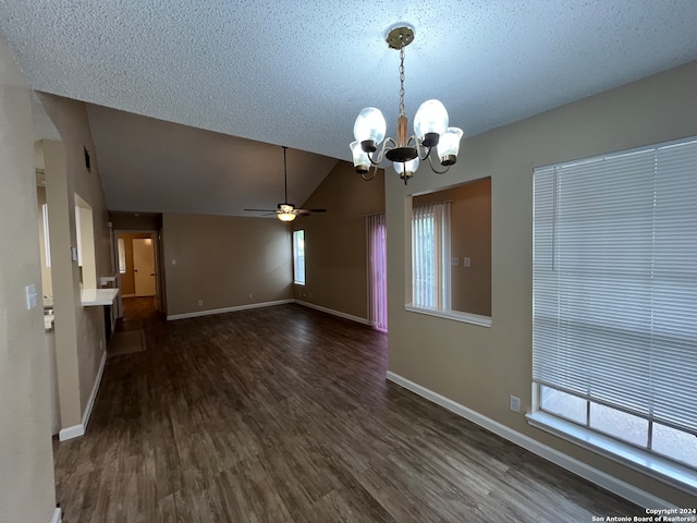 empty room featuring lofted ceiling, ceiling fan with notable chandelier, dark hardwood / wood-style floors, and a textured ceiling