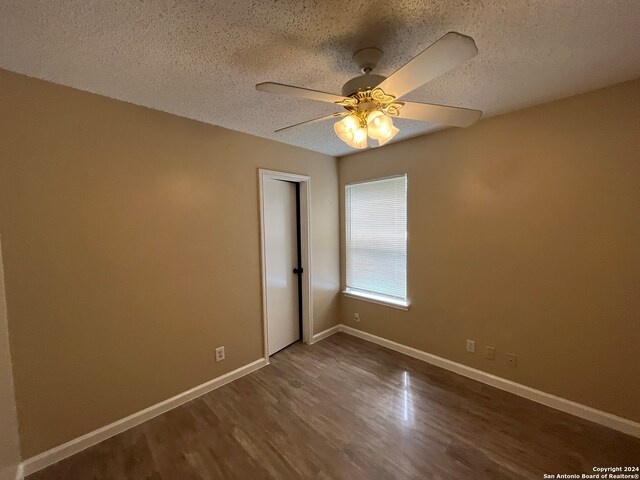 unfurnished room featuring ceiling fan, dark hardwood / wood-style floors, and a textured ceiling