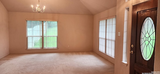 carpeted foyer featuring lofted ceiling and an inviting chandelier