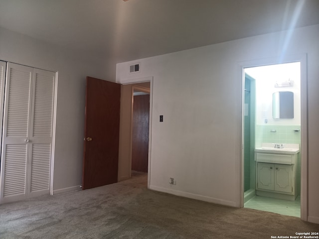 unfurnished bedroom with a closet, carpet, sink, and ensuite bathroom