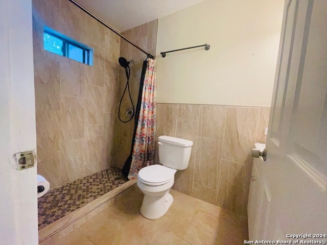 bathroom with tile walls, a shower with shower curtain, tile floors, and toilet