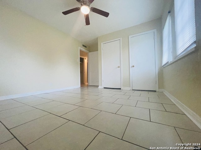 unfurnished bedroom with ceiling fan and light tile flooring