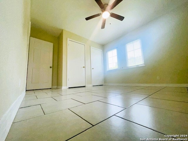 unfurnished bedroom with ceiling fan and light tile flooring