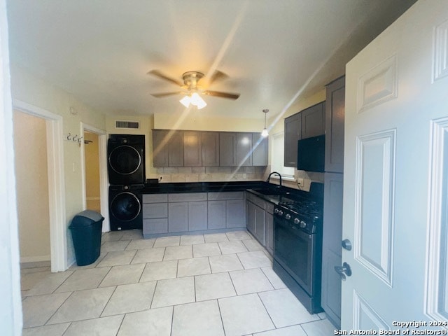 kitchen with dishwashing machine, ceiling fan, light tile flooring, sink, and stacked washer and clothes dryer