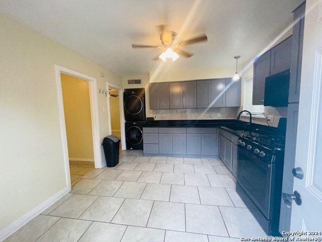 kitchen with stacked washer and clothes dryer, ceiling fan, light tile floors, gas range, and hanging light fixtures