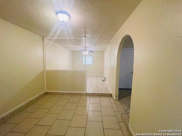 empty room with a textured ceiling and light tile flooring