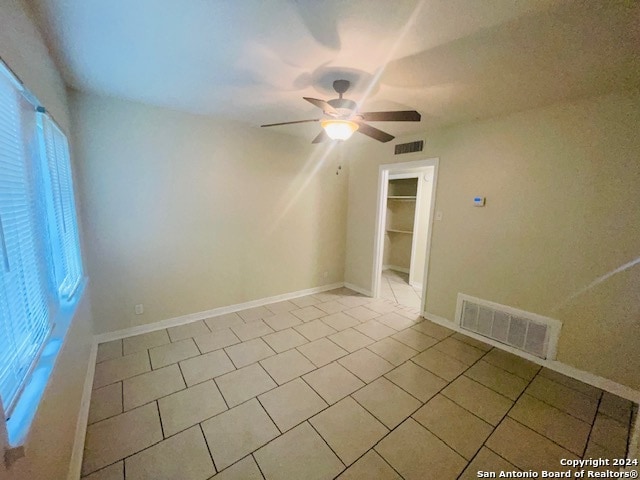 empty room with ceiling fan and light tile floors