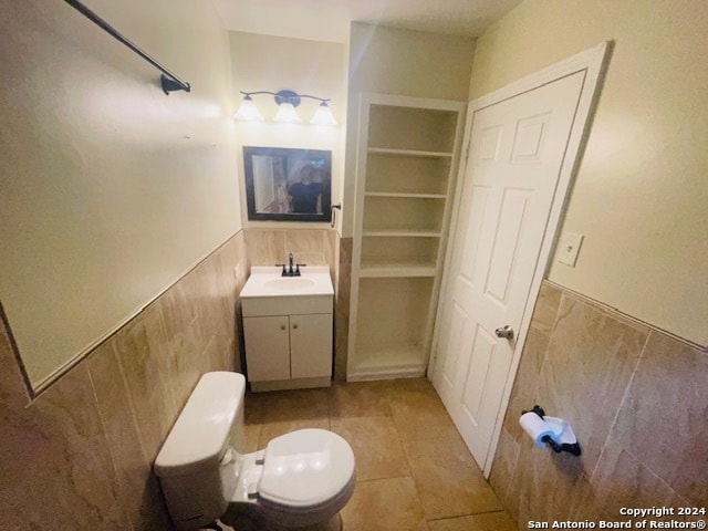 bathroom with built in features, vanity, toilet, and tile floors