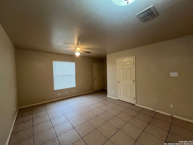 tiled empty room featuring a textured ceiling and ceiling fan