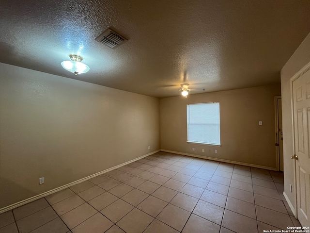 spare room featuring a textured ceiling, ceiling fan, and light tile floors
